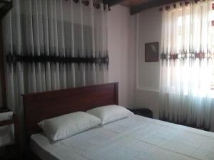 马特莱Walawwa Guest House的一间卧室配有一张带白色床单和窗帘的床