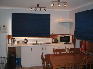 德文特布里奇德文特大桥别墅酒店的一间带桌子的厨房和一间带蓝百叶窗的厨房