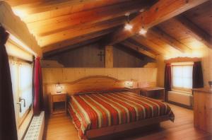 绍里斯Hotel Garni Plueme的一间带一张床的卧室,位于带木制天花板的房间内
