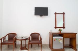 金瓯宋红酒店的一间设有两把椅子、一张桌子和一台电视的房间