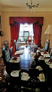 巴纳赫Charlotte's Way B&B的一间设有长桌和红色窗帘的用餐室