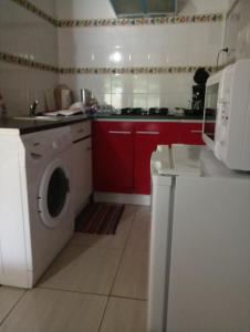 锡拉奥莱斯克里奥尔花园公寓的厨房配有洗衣机和红色橱柜。