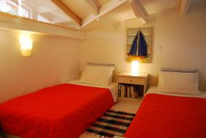 考考纳里斯Skiathos Driades的小客房内的两张床,配有红色床单