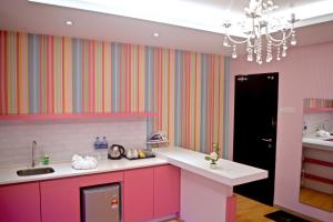 怡保博德标志性套房酒店的厨房配有粉红色橱柜、水槽和吊灯。