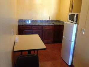 梅萨梅萨绿洲汽车旅馆的厨房配有冰箱、桌子和微波炉
