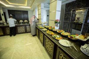 代瓦西尔干河Rest Night Hotel Apartments Wadi Al Dawasir的站在食物自助餐前的人