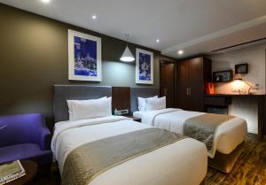 加尔各答Howard Johnson by Wyndham, Kolkata Airport的酒店客房设有两张床和一张紫色沙发