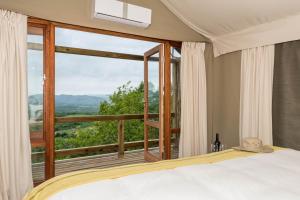 白河Muluwa Lodge的一间卧室设有一张床和一个大窗户
