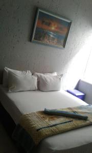 约翰内斯堡Royal Crown Guesthouse的一张带白色枕头的床和一张墙上的照片