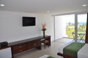 TubaráHotel Isla Verde的一间卧室配有一张床、一张书桌和一个窗户。