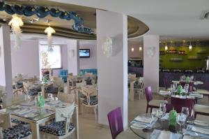 TubaráHotel Isla Verde的餐厅配有白色桌子和紫色椅子