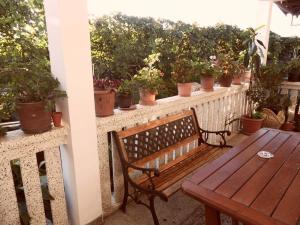 巴统Guest HAUSE LOS ANGISA的木凳坐在种植了盆栽植物的阳台