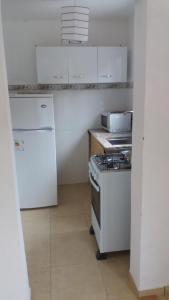 皮里亚波利斯Apartamentos del Este的白色的厨房配有炉灶和冰箱。