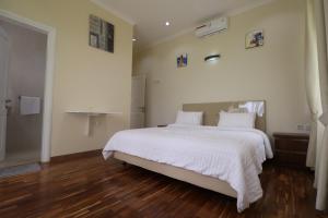 普卡Diyar Villas Puncak NB3/3的卧室配有一张白色的大床,铺有木地板