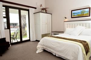 韦尔德里夫Riviera Hotel & Chalets的一间带一张白色大床的卧室和一个阳台
