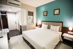 雅加达快乐驿站酒店的一间卧室设有一张大床和蓝色的墙壁