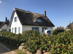 格洛韦Ferienhaus Insel Ruegen Ostsee Reethaus am Meer的白色的房子,有茅草屋顶和一些花