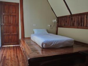 班康卡臣班马卡自然旅馆的一间卧室配有一张床,铺有木地板