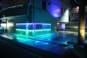 Hakonegasaki露台M横田基地酒店（仅限成人）的一座带蓝色和紫色灯光的游泳池的建筑
