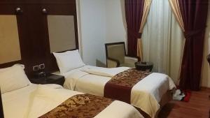 科威特拉奥姆旅馆的酒店客房,配有两张床和椅子