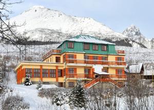 Vysoke Tatry - Horny SmokovecMiramonti Penzión的雪中的房子,背景是山