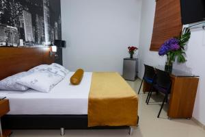 麦德林苏斯埃斯塔迪奥酒店的卧室配有一张床和一张桌子及椅子