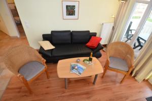 奥斯赛拜-塞林Villa Seerose - Appartement 17的客厅配有黑色沙发和两把椅子