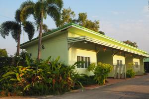 乌隆他尼555 Resort的一座黄色的房子,屋顶绿荫环绕,棕榈树环绕