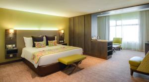 内罗毕罗望子树酒店的酒店客房设有一张大床和一张书桌。