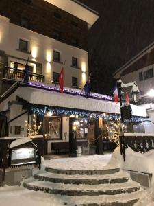 布勒伊-切尔维尼亚Hotel Edelweiss 3 Stelle SUPERIOR的雪地里一座带圣诞灯和楼梯的建筑
