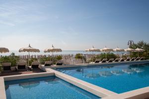 利多迪耶索罗德尔纳西奥尼酒店的一个带椅子和遮阳伞的游泳池以及大海