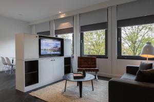 海牙肯尼迪B-公寓式酒店的客厅配有电视、沙发和桌子
