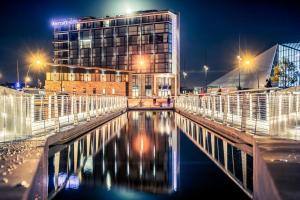 瑟堡瑟堡中心港口美居酒店的一座晚上有水的建筑