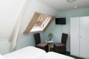 Anderen德和勃艮万安得润酒店的一间卧室设有窗户、两把椅子和一张桌子
