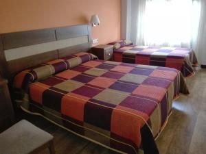 Castañares de Rioja老板旅馆的酒店客房设有两张床和窗户。