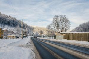 乌帕河畔斯沃博达Penzion SPORTINO的一条雪覆盖的道路,汽车驶向这条道路