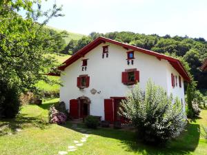 圣艾蒂安德拜戈里Chambres d'hôtes Idiartekoborda的白色的房子,有红色百叶窗和树木