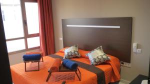 罗萨里奥港海滩附近2V豪华公寓 的一间卧室配有橙色床和两把椅子