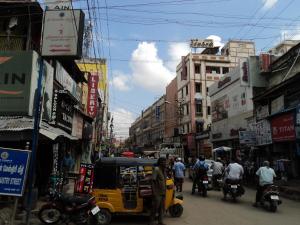 马杜赖Mani's residency的一条繁忙的城市街道,人们骑摩托车和汽车