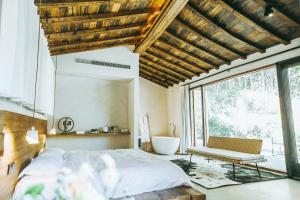 德清柒竹·悠南山的一间卧室配有一张床、一张长凳和一个窗户。