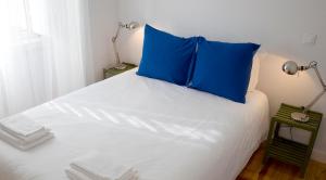 阿尔马达卡西利亚什公寓旅馆的床上有蓝色枕头
