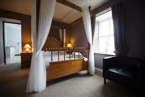 海菲尔德兰特派克旅馆的一间卧室配有带窗帘的天蓬床和窗户。