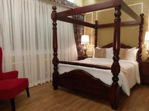 大雅台Lee Boutique Hotel Tagaytay的一间卧室配有四柱床和红色椅子