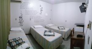 沃尔塔雷东达Pousada Casagrande - São João的一间设有三张床的客房,墙上有标志