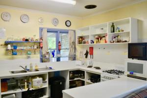 阿波罗湾阿波罗湾青年旅舍的厨房配有白色橱柜和墙上的时钟