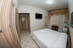 阿西斯圣罗莎酒店的卧室配有白色的床和电视。
