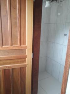 瓜拉图巴Hotel Pousada Guaratuba的一间带淋浴的浴室,位于木门旁