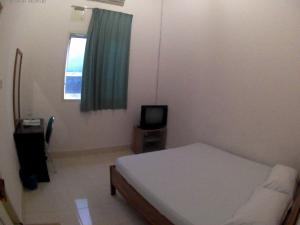 万慈威斯马哈拉尼旅馆的一间小卧室,配有一张床和电视