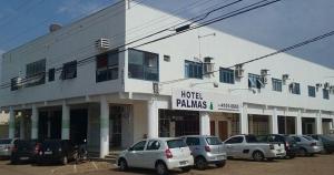 帕尔马斯Hotel Palmas Tocantins的白色的建筑,有汽车停在停车场