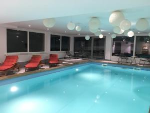 希洛谢克Hotel Gemma- Adults only的一个带红色椅子和灯光的大型游泳池